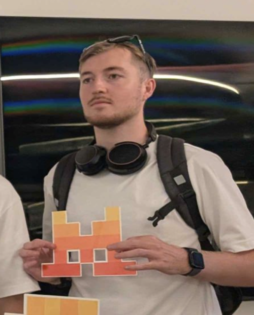 Mathieu at a hackathon holding a pixel-art invader